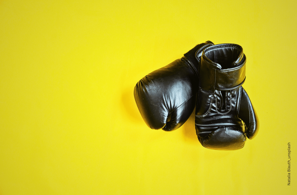 Schwarze Lederboxhandschuhe auf knallgelbem Hintergrund.
